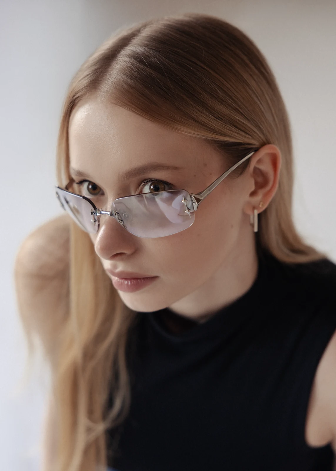 Portrait of Alex, wearing rimless glasses, softly lit against a plain light backdrop.